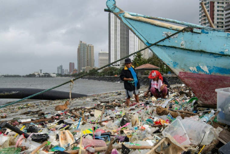 Des personnes ramassent des matériaux recyclables dans les déchets échoués le long de la baie de Manille, le 10 novembre 2025, après le passage du super typhon Fung-wong qui a balayé la capitale pendant la nuit ( AFP / Ted ALJIBE )