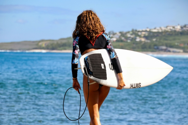 Une surfeuse tient sa planche équipée d'un dispositif antirequins, à Saint-Leu, à La Réunion, le 2 avril 2021 ( AFP / Richard BOUHET )