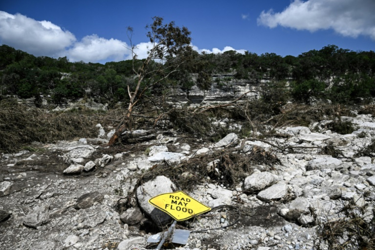 Un panneau de signalisation à terre prévenant que la route peut être inondée, à côté du fleuve Guadalupe au Texas, le 8 juillet 2025, à la suite d'inondations meurtrières ( AFP / RONALDO SCHEMIDT )