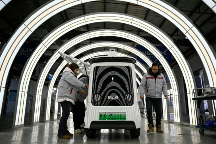 Des ouvriers travaillent sur une ligne de production de l'usine Neolix qui fabrique de petits véhicules utilitaires autonomes pour le transport de colis en ville, le 4 décembre 2025 à Yancheng dans la province chinoise du Jiangsu  ( AFP / Jade GAO )