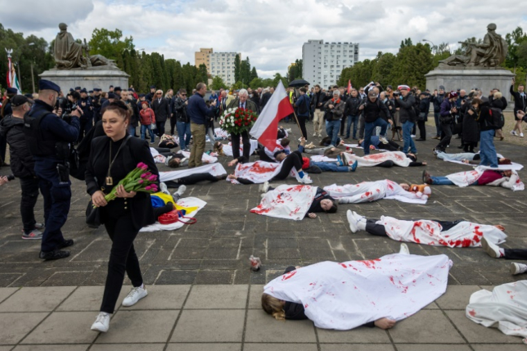 Des manifestants allongés sur le sol, simulent des corps de victimes, pour protester contre l'invasion russe de l'Ukraine, au mausolée des soldats soviétiques à Varsovie, en Pologne, le 9 mai 2025 ( AFP / Wojtek RADWANSKI )