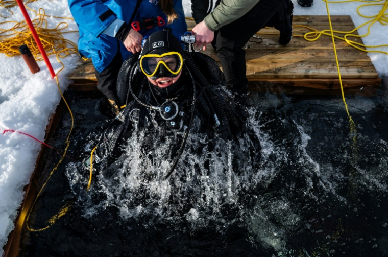 Un plongeur participe à un stage scientifique de plongée polaire, le 14 mars 2026 dans le lac de Kilpisjärvi, à l'extrême nord-ouest de la Finlande ( AFP / John MACDOUGALL )