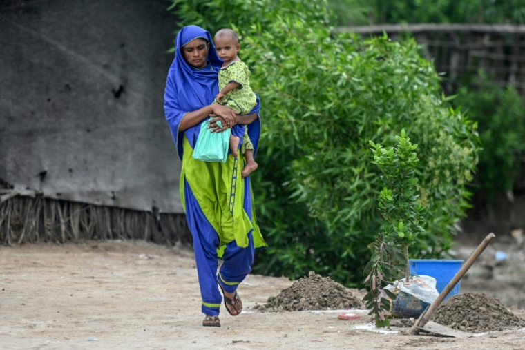 Une femme enceinte, en enfant dans les bras, arrive pour participer au programme de nutrition de l'Unicef au village de Fateh Muhammad Soomro, dans la province du Sindh, le 29 juillet 2025 au Pakistan ( AFP / Rizwan TABASSUM )