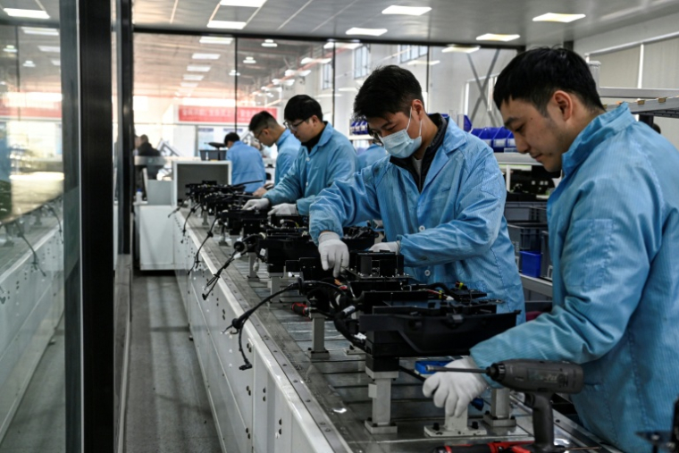 Des ouvriers travaillent sur une ligne de production de l'usine Neolix qui fabrique de petits véhicules utilitaires autonomes pour le transport de colis en ville, le 4 décembre 2025 à Yancheng dans la province chinoise du Jiangsu  ( AFP / Jade GAO )