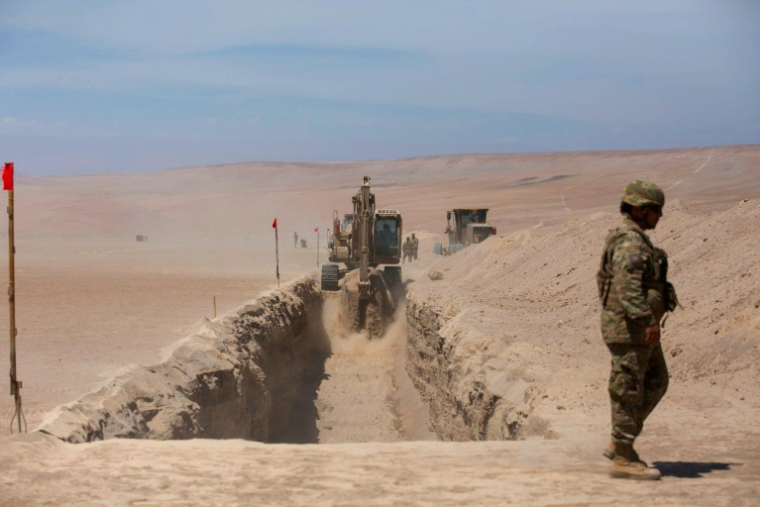 Un soldat monte la garde près d'engins de chantier opérant près du poste frontalier de Chacalluta, à la frontière entre le Chili et le Pérou, le 16 mars 2026 ( AFP / Patricio BANDA )