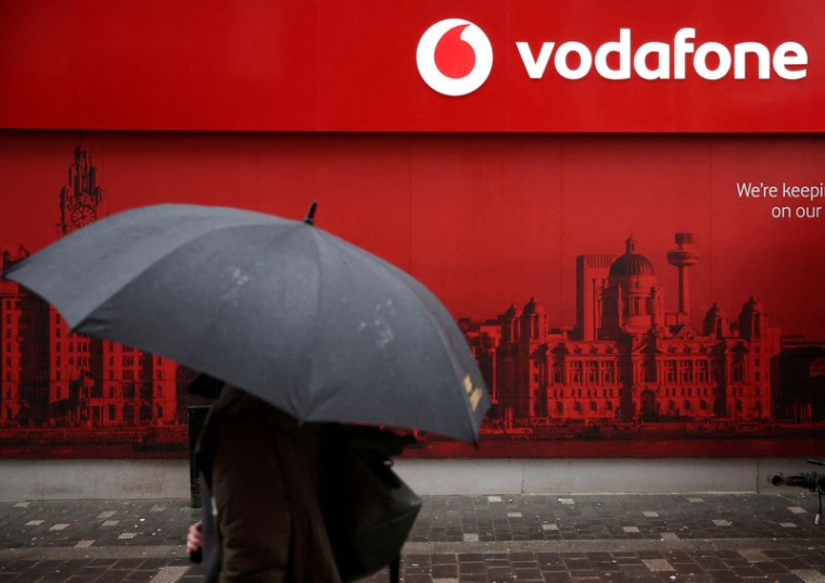 Un homme utilise un parapluie alors qu'il passe devant un magasin de téléphonie mobile Vodafone à Liverpool