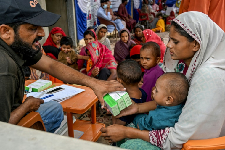 Un travailleur social donne des médicaments à une mère après avoir examiné son enfant lors d'un programme de nutrition de l'Unicef au village de Fateh Muhammad Soomro, dans la province du Sindh, le 29 juillet 2025 au Pakistan ( AFP / Rizwan TABASSUM )