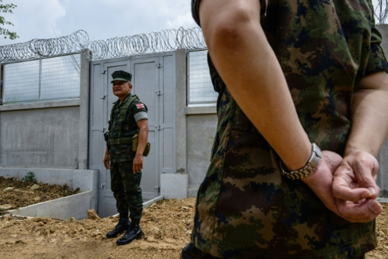 Le capitaine Prachya Hantiem (g), commandant d'une force de la Marine royale, devant un mur en béton installé par l'armée thaïlandaise à la frontière entre la Thaïlande et le Cambodge, dans le district de Pong Nam Ron, le 10 septembre 2026 en Thaïlande ( AFP / ANTHONY WALLACE )