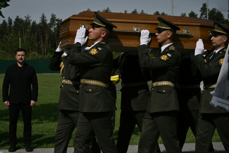 Le président ukrainien Volodymyr Zelensky (g) participe à la cérémonie de réinhumation du leader nationaliste controversé Andriï Melnyk, décédé en 1964 et ancien chef d'une branche de l'Organisation des nationalistes ukrainiens (OUN), ainsi que de son épouse Sofia, au cimetière national militaire commémoratif près de Kiev, le 25 mai 2026 ( AFP / Genya SAVILOV )