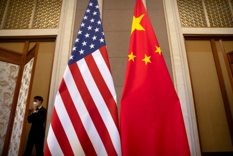 Photo d'archives: Un membre du personnel portant un masque passe devant les drapeaux américains et chinois