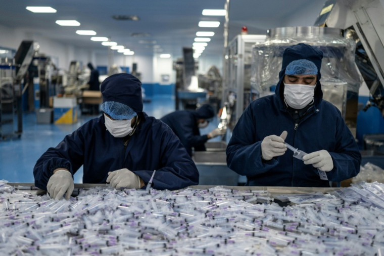 Des ouvriers assemblent et emballent des seringues jetables à l'usine pharmaceutique Milli Shifa (MSP), en périphérie de Kaboul, le 3 février 2026 en Afghanistan ( AFP / Wakil KOHSAR )