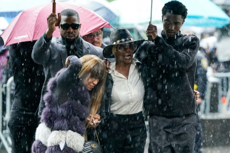 King Combs (d), fils de P. Didddy (Sean Combs), tient un parapluie pour Janice Combs, la mère du rappeur visé par un procès, alors qu'ils arrivent au tribunal fédéral à New York, le 14 mai 2025 ( AFP / TIMOTHY A. CLARY )
