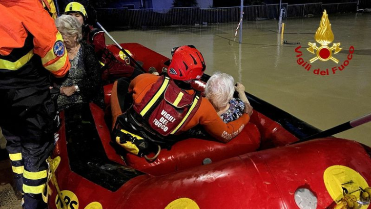 Des secouristes sauvent des personnes sur un canot pneumatique dans une rue inondée après les fortes pluies qui ont frappé la côte est de la région des Marches à Senigallia, en Italie