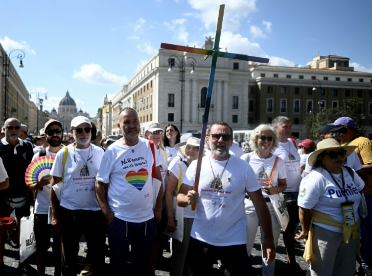 Derrière une croix aux couleurs de l'arc-en-ciel, des pèlerins catholiques LGBT+ ont remonté samedi après-midi la principale artère menant au Vatican pour franchir la "Porte sainte" de l'imposante basilique Saint-Pierre ( AFP / Filippo MONTEFORTE )