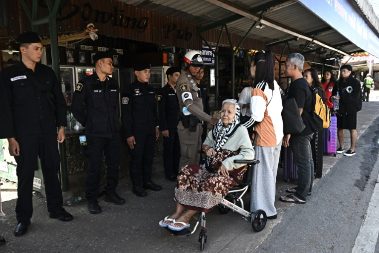 Un policier thaïlandais échange avec des personnes qui attendent de traverser le poste-frontière international de Ban Khlong Luek entre la Thaïlande et le Cambodge, dans le district d'Aranyaprathet, en Thaïlande, le 24 juin 2025 ( AFP / Lillian SUWANRUMPHA )