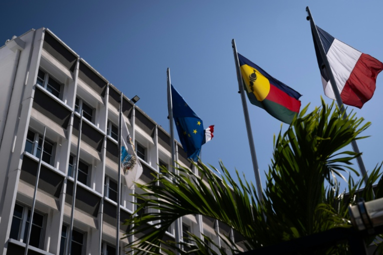 Un drapeau kanak (2e d), le drapeau français (d) et le drapeau européen (2eg) devant l'hôtel de ville de Nouméa, en Nouvelle-Calédonie, le 23 septembre 2024 ( AFP / SEBASTIEN BOZON )