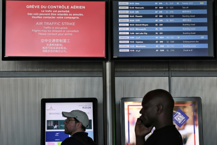 Des passagers consultent le tableau d'affichage des départs à l'aéroport Roissy Charles-de-Gaulle, près de Paris, pendant la grève des contrôleurs aériens français, le 3 juillet 2025 ( AFP / Thibaud MORITZ )