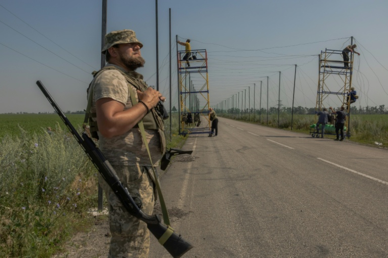 Un soldat ukrainien monte la garde tandis que d'autres soldats installent des filets anti-drone dans la région de Donetsk, le 8 juillet 2025. ( AFP / Roman PILIPEY )