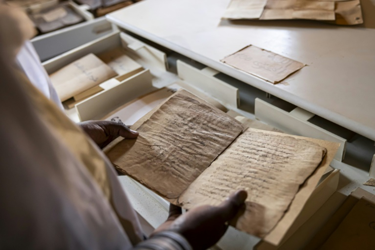 Mohamed Ben Baty contemple un très ancien manuscrit, le 4 avril 2025, dans la ville médiévale de Oualata, en Mauritanie ( AFP / PATRICK MEINHARDT )
