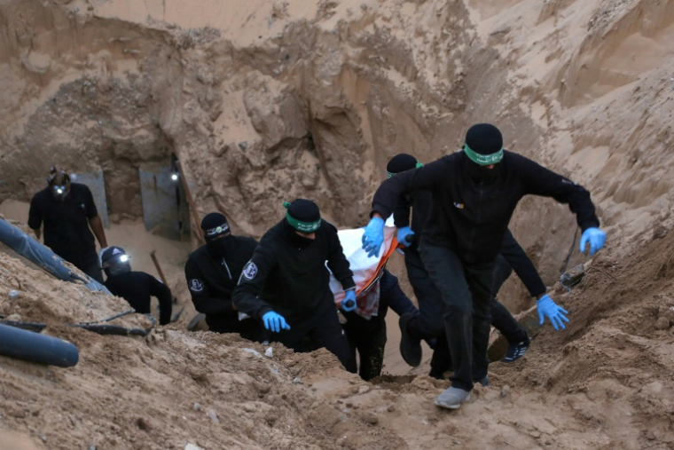 Des combattants armés et cagoulés du Hamas transportent un corps retrouvé dans un tunnel au nord de Khan Younès, dans le sud de la bande de Gaza, le 28 octobre 2025  ( AFP / Bashar TALEB )