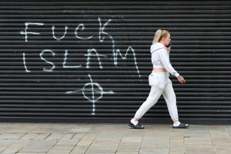 Un graffiti anti-islamique sur un rideau métallique, au lendemain de manifestations qui ont dégénéré en violences à Belfast, en Irlande du Nord, le 10 juin 2026 ( AFP / Paul Faith )
