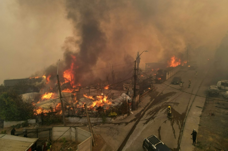 Sur cette vue aérienne, de la fumée et des flammes s’échappent de maisons en feu lors d’un incendie de forêt à Concepción, au Chili, le 18 janvier 2026 ( AFP / GUILLERMO SALGADO )