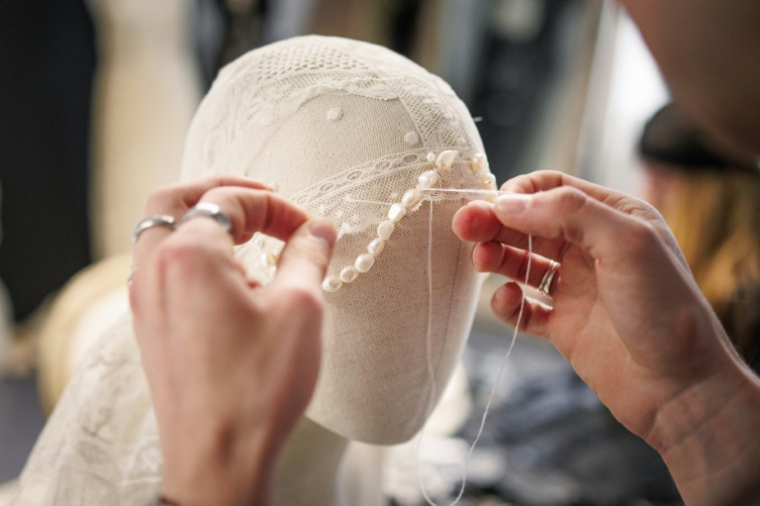 Une couturière travaille sur une pièce de dentelle dessinée par la styliste espagnole Maria Bernad, fondatrice de l'atelier Les Fleurs Studio, le 5 mai 2026 à Paris ( AFP / SIMON WOHLFAHRT )