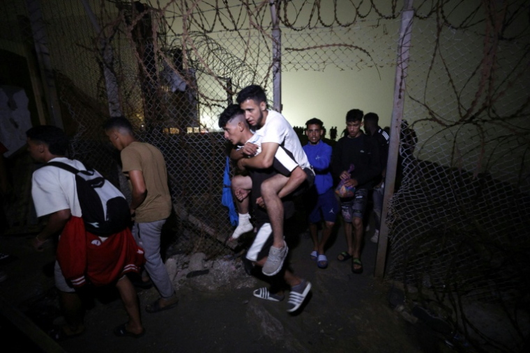 Des migrants regagnent Fnideq, la ville marocaine qui jouxte l'enclave espagnole de Ceuta où des milliers de candidats marocains à l'émigration avaient afflué ces derniers jours, le 1er août 2026le 1er août 2026 à  ( AFP / Abdel Majid BZIOUAT )