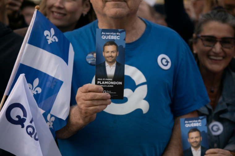 Un sympathisant tient un tract à l'effigie du chef du Parti québécois (PQ), Paul St-Pierre Plamondon, devant la Maison de Radio-Canada à Montréal, dans la province de Québec au Canada, le 23 septembre 2026 ( AFP / Alexis Aubin )