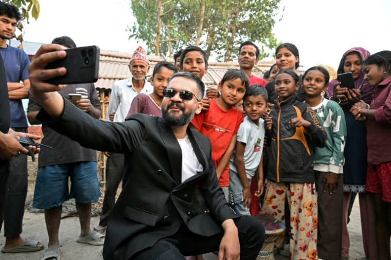 Balendra Shah (2e g), candidat duParti national indépendant (RSP, centriste), fait un selfie avec des enfants lors de sa campagne électorale à Gauriganj, dans le district de Jhapa, le 16 février 2026 ( AFP / PRAKASH MATHEMA )