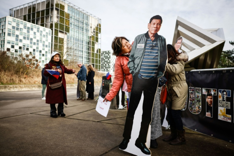 Une manifestante tient une silhouette en carton grandeur nature de l'ancien président philippin Rodrigo Duterte lors d'une manifestation de soutien devant la Cour pénale internationale (CPI), où se tiennent les audiences de confirmation des charges visant à détailler les accusations de crimes contre l'humanité qui le vise, à La Haye, le 23 février 2026 ( AFP / Simon Wohlfahrt )
