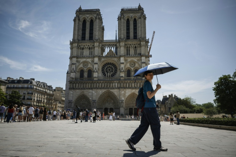 Un touriste se protège du soleil devant la cathédrale Notre-Dame de Paris, le 28 mai 2026 ( AFP / Simon WOHLFAHRT )