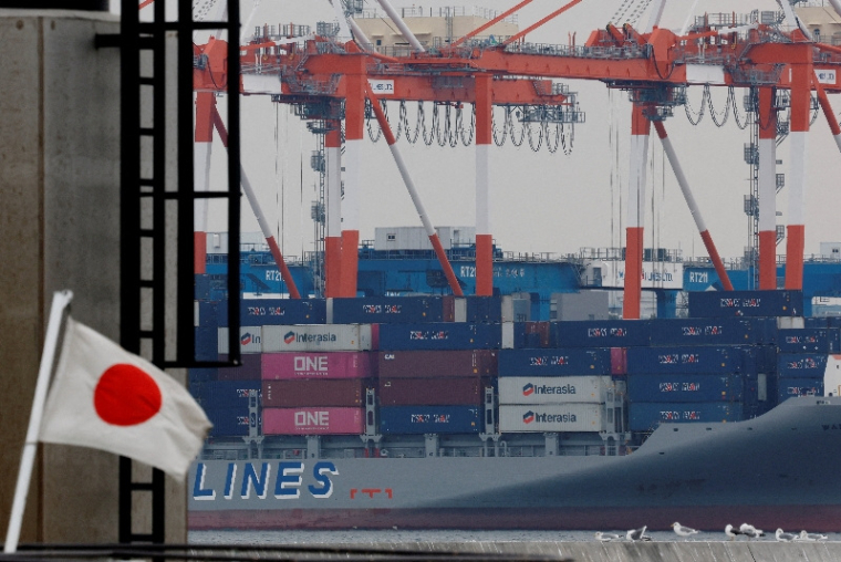 Un drapeau national japonais flotte des conteneurs de marchandises dans un port industriel de Tokyo