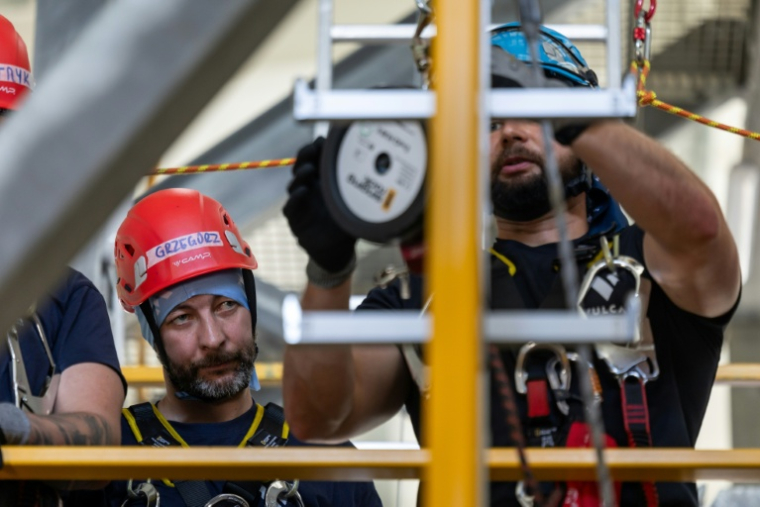 Le mineur Grzegorz Witek (g), participant au programme de formation pour techniciens d'éoliennes, lors d'un stage sur la sécurité, le sauvetage et l'évacuation en hauteur au centre de formation Vulcan à Szczecin, dans le nord-ouest de la Pologne, le 23 juin 2026 ( AFP / Wojtek RADWANSKI )