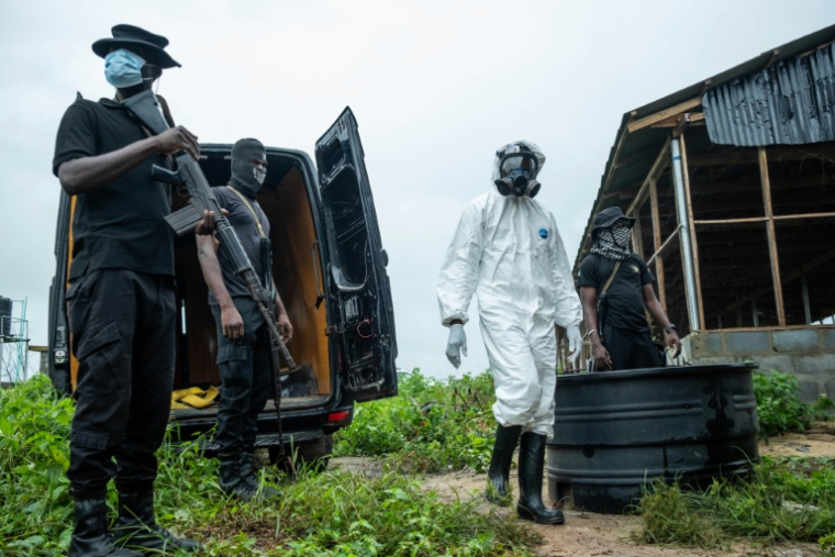 Des membres de l'Agence nationale nigériane de lutte contre les stupéfiants (NDLEA) se tiennent devant un laboratoire clandestin de méthamphétamine abandonné, lors d'une opération visant à démanteler le site à Iroto, dans l'Etat d'Ogun, le 29 juillet 2026 ( AFP / TOYIN ADEDOKUN )