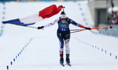 Julia Simon franchit en tête la ligne d'arrivée du relais féminin, remporté par la France le 18 février aux JO de Milan Cortina. ( AFP / FRANCK FIFE )