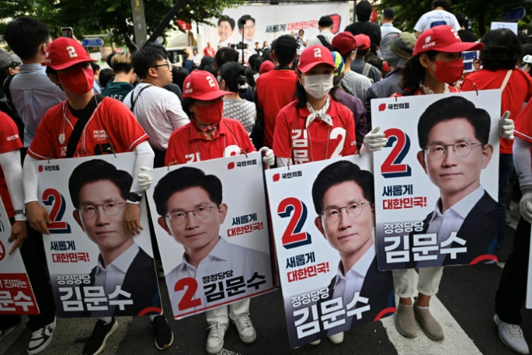 Des soutiens du candidat du Parti du Pouvoir au peuple à la présidence sud-coréenne, Kim Moon-soo, avec des pancartes à son effigie alors qu'ils participent à un événement de campagne électorale à Séoul, le 1er juin 2025 ( AFP / Pedro PARDO )