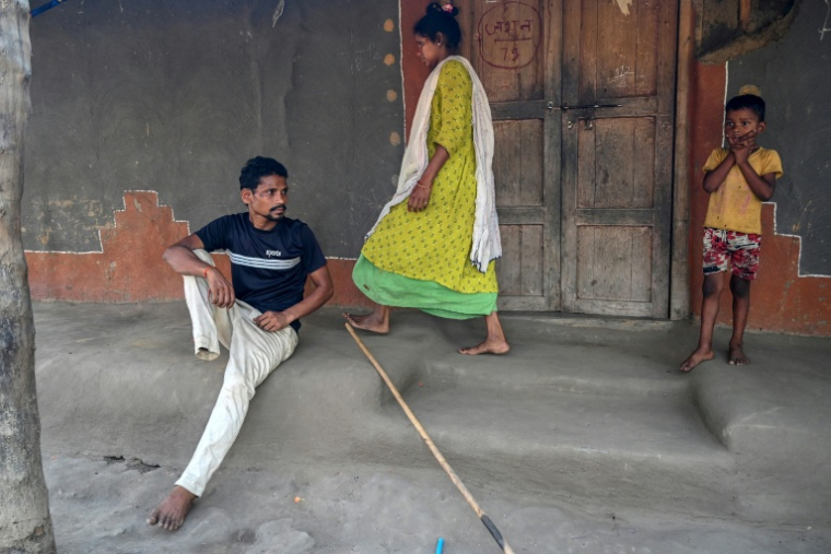 Raju Modiyam (g), qui a perdu une jambe dans l'explosion d'une mine artisanale, avec sa femme Jayamma (c) et leur enfant chez eux dans le village de Lankapalli du district de Bijapur, dans l'Etat de Chhattisgarh, le 1er avril 2026 en Inde ( AFP / Shammi MEHRA )