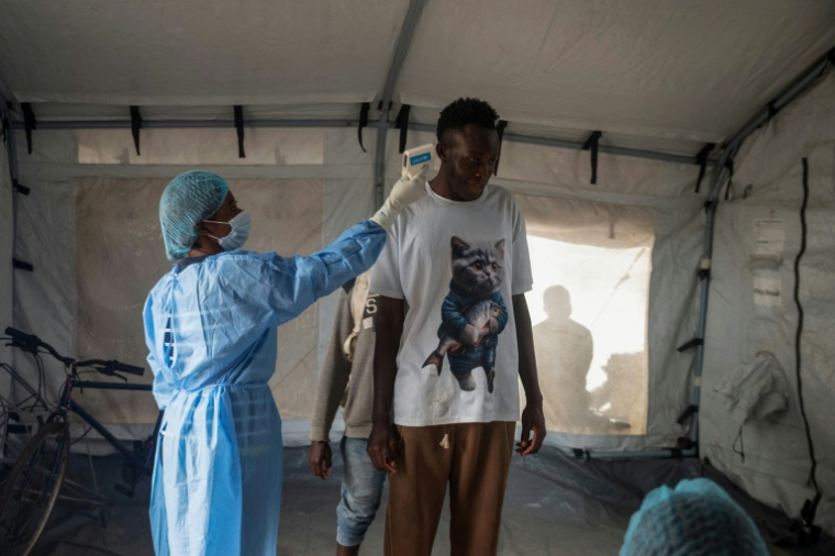 Une agente de santé prend la température d’un voyageur à son arrivée au débarcadère de M’Poko Bac, dans le district de Bimbo, au sud-ouest de Bangui, le 28 octobre 2026 en Centrafrique ( AFP / - )