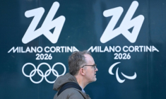 Une personne passe devant les logos des Jeux olympiques et paralympiques d'hiver de Milan Cortina, à Milan, le 5 février 2026 ( AFP / Daniel MUNOZ )