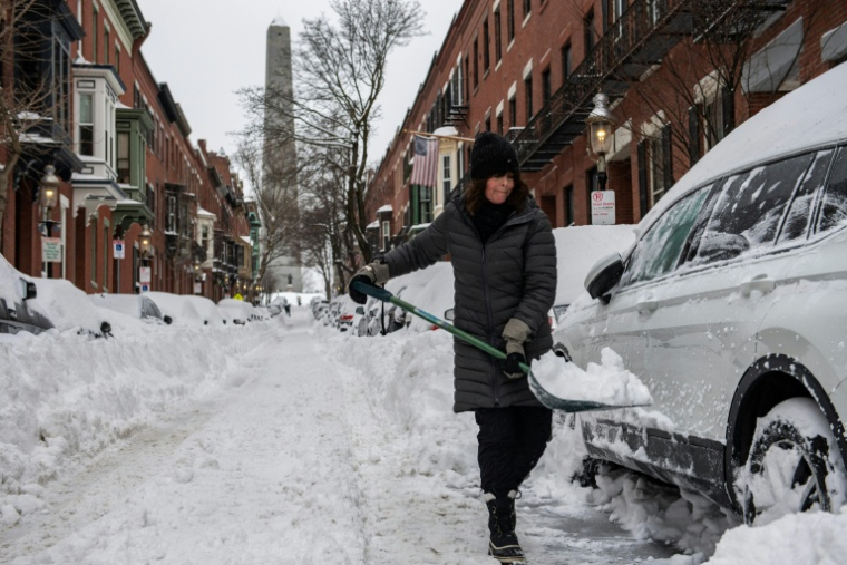 Une femme déneige la route à Boston, le 26 janvier 2026 dans le Massachusetts ( AFP / Joseph Prezioso )