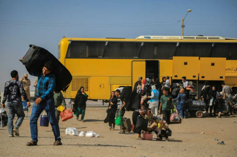 Un bus iranien dépose des réfugiés afghans à la frontière d'Islam Qala, dans la province d'Herat, le 24 juillet 2025 en Afghanistan ( AFP / Mohsen KARIMI )