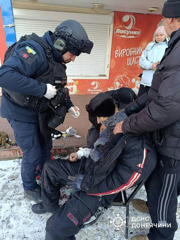 Photo diffusée par le Service national des situations d'urgence d'Ukraine, le 4 février 2026, montrant un secouriste ukrainien portant assistance à un civil blessé après une frappe russe sur la ville de Druzhkivka, dans la région de Donetsk ( STATE EMERGENSY SERVICE OF UKRAINE / Handout )
