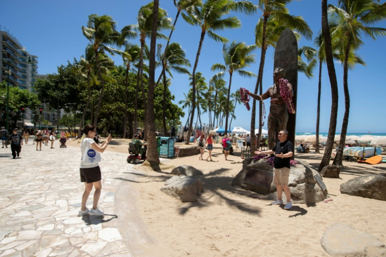 Des personnes prennent des photos devant la statue de Duke Kahanamoku sur la plage de Waikiki à Honolulu, Hawaï, le 14 août 2026 ( AFP / Eugene Tanner )