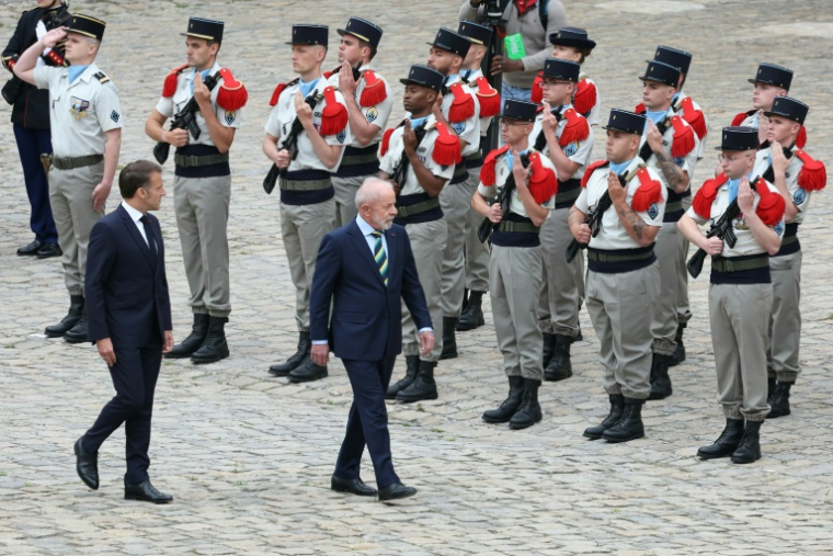 Le président français Emmanuel Macron (g) et son homologue brésilien Luiz Inácio Lula da Silva passent en revue la Garde d'honneur lors d'une cérémonie à l'hôtel des Invalides, le 5 juin 2025 à Paris ( AFP / Thomas SAMSON )