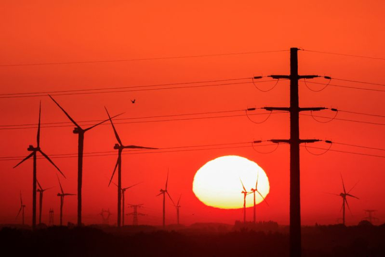 Des éoliens et des pylônes électriques sont photographiés au lever du soleil