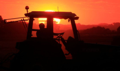 Après avoir récolté son champ de blé, un agriculteur ramasse la paille au coucher du soleil pour former des balles, à Haynecourt