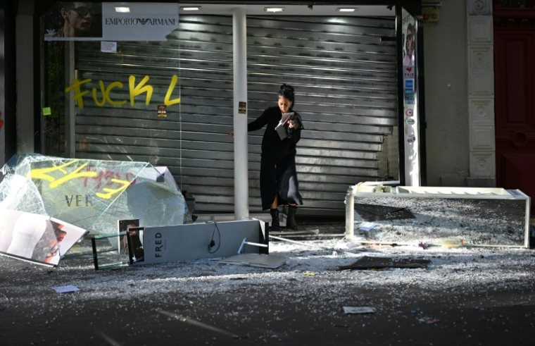 Une commerçante devant sa boutique endommagée au lendemain d'une manifestation contre le vie chère, le 18 octobre 2026 à Paris ( AFP / Matthieu RONDEL )