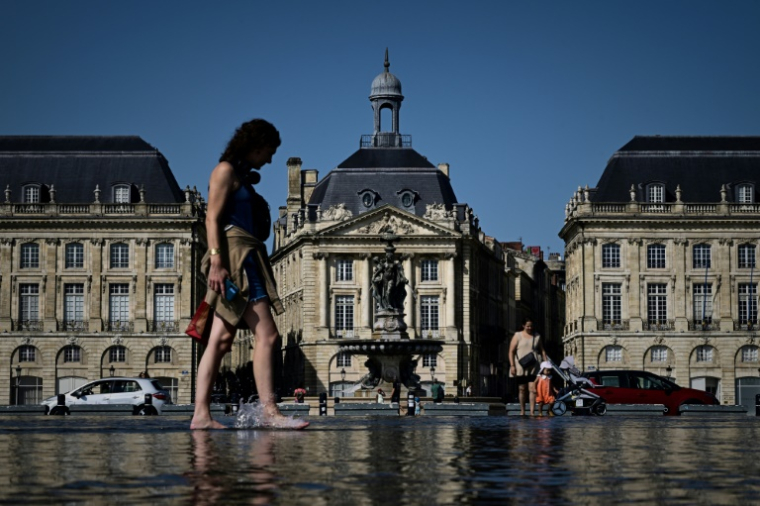 Une femme se rafraichit sur le miroir d'eau de Bordeaux, le 8 août 2025 ( AFP / Philippe LOPEZ )