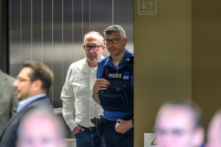 Le maire de Crans-Montana, Nicolas Feraud (g), escorté par un policier lors d'une suspension d'audience dans le cadre de l'enquête sur l'incendie au bar Le Constellation pendant les fêtes du Nouvel An, le 13 avril 2026 à Sion, en Suisse ( AFP / Fabrice COFFRINI )